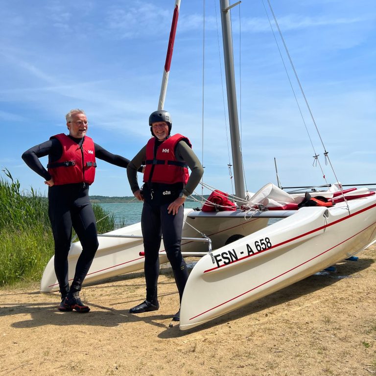 Segelschüler von Sweet Water Adventures vor einem Katamaran